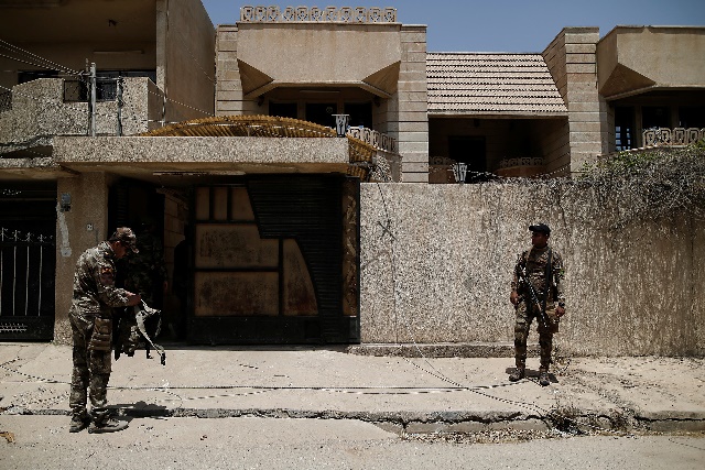 Soldados de la 9ª División Blindada del Ejército iraquí frente a la casa que el Estado Islámico utilizó como prisión.