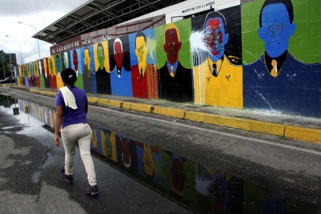 A woman walks next to a mural depicting Venezuela's late President Hugo Chavez in Barinas, Venezuela June 14, 2017. Picture taken June 14, 2017. REUTERS/Carlos Eduardo Ramirez