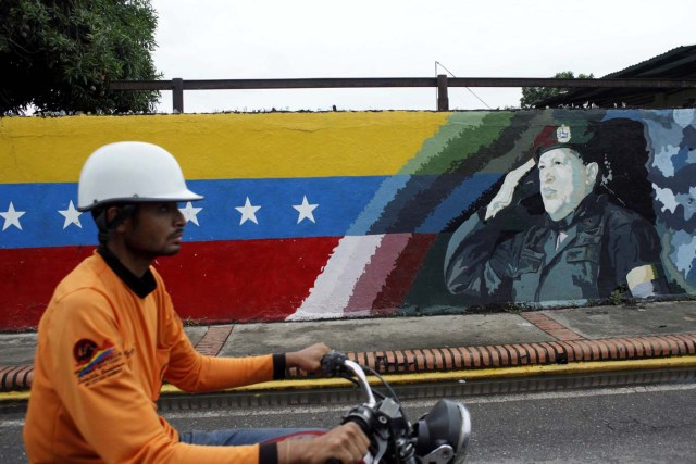 A motorcyclist rides past a mural depicting Venezuela's late President Hugo Chavez in Sabaneta, Venezuela June 13, 2017. Picture taken June 13, 2017. REUTERS/Carlos Eduardo Ramirez