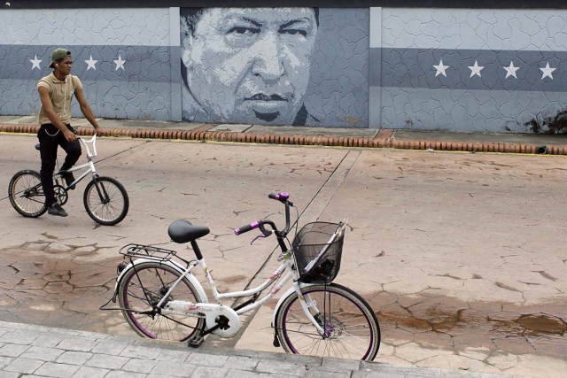 A man rides a bicycle in front a mural depicting Venezuela's late President Hugo Chavez in Sabaneta, Venezuela June 13, 2017. Picture taken June 13, 2017. REUTERS/Carlos Eduardo Ramirez