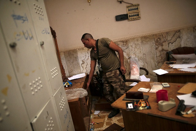 Soldado iraquí fotografiado mientras registraba uno de los escritorios de los yihadistas.