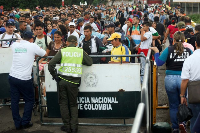 A Colombian police officer and a migration officer stand in front of people who are attempting to cross into Colombia from Venezuela through Simon Bolivar international bridge, at Cucuta, Colombia, July 25, 2017. REUTERS/Luis Parada