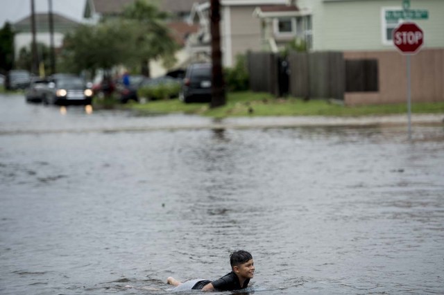 A boy plays in a flooded street as the effects of Hurricane Harvey are seen August 26, 2017 in Galveston, Texas. Hurricane Harvey left a trail of devastation Saturday after the most powerful storm to hit the US mainland in over a decade slammed into Texas, destroying homes, severing power supplies and forcing tens of thousands of residents to flee. / AFP PHOTO / Brendan Smialowski / ?The erroneous mention appearing in the metadata of this photo by Brendan Smialowski has been modified in AFP systems in the following manner: [Hurricane Harvey] instead of [Hurricane Henry]. Please immediately remove the erroneous mention from all your online services and delete it from your servers. If you have been authorized by AFP to distribute it to third parties, please ensure that the same actions are carried out by them. Failure to promptly comply with these instructions will entail liability on your part for any continued or post notification usage. Therefore we thank you very much for all your attention and prompt action. We are sorry for the inconvenience this notification may cause and remain at your disposal for any further information you may require.?