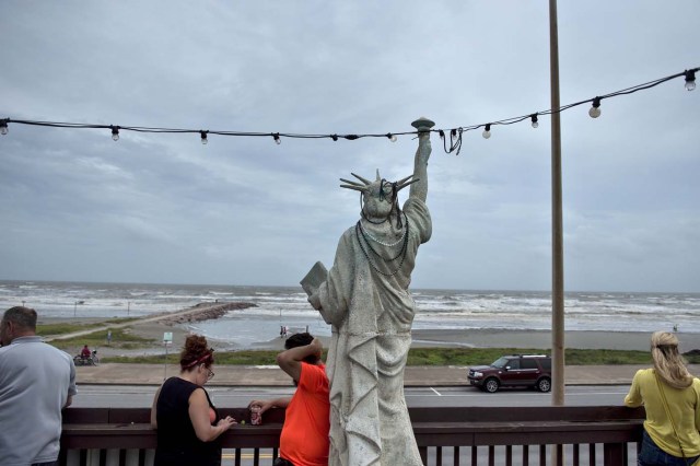 People look out from a bar to the Gulf of Mexico as the effects of Hurricane Harvey are seen August 26, 2017 in Galveston, Texas. Hurricane Harvey left a deadly trail of devastation Saturday in Texas, as officials warned of "catastrophic" flooding and said that recovering from the most powerful storm to hit the United States in more than a decade could take years. / AFP PHOTO / Brendan Smialowski / ?The erroneous mention[s] appearing in the metadata of this photo by Brendan Smialowski has been modified in AFP systems in the following manner: [Hurricane Harvey] instead of [Hurricane Henry]. Please immediately remove the erroneous mention[s] from all your online services and delete it from your servers. If you have been authorized by AFP to distribute it to third parties, please ensure that the same actions are carried out by them. Failure to promptly comply with these instructions will entail liability on your part for any continued or post notification usage. Therefore we thank you very much for all your attention and prompt action. We are sorry for the inconvenience this notification may cause and remain at your disposal for any further information you may require.?