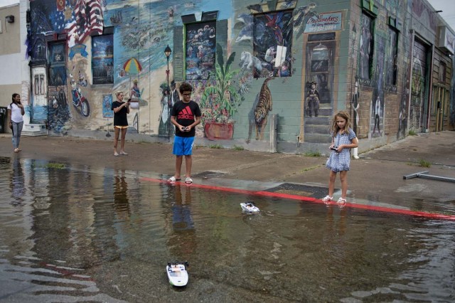 Children play in a flooded road following the passage of Hurricane Harvey on August 26, 2017 in Galveston, Texas. / AFP PHOTO / Brendan Smialowski