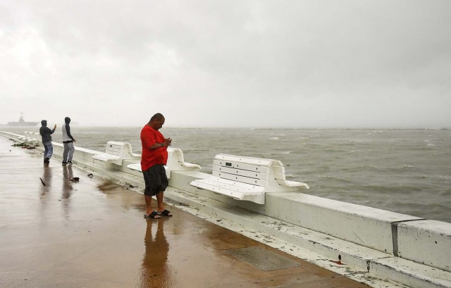 Joe Ray (R), takes a photo of the waves generated by Hurricane Harvey in Corpus Christi, Texas, U.S. August 25, 2017. REUTERS/Mohammad Khursheed