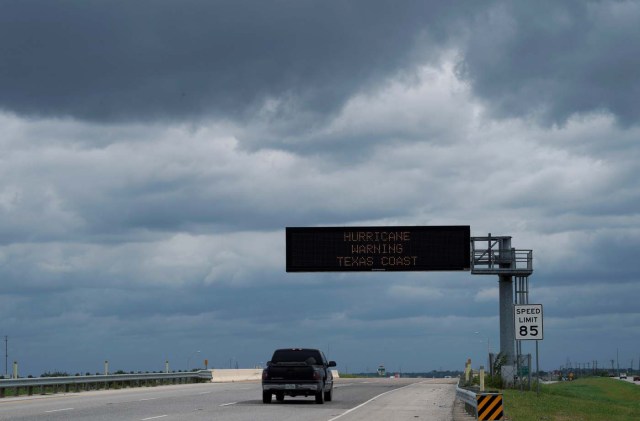 A vehicle passes a hurricane warning sign under storm clouds as it heads south approaching Victoria, Texas, U.S. August 25, 2017. REUTERS/Rick Wilking