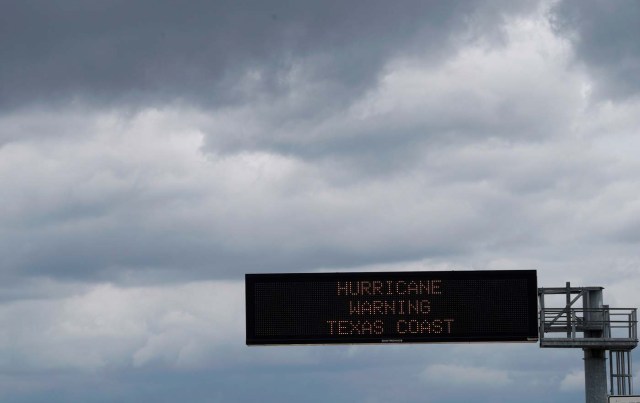 A hurricane warning sign is seen under storm clouds, above a highway approaching Victoria, Texas, U.S. August 25, 2017. REUTERS/Rick Wilking