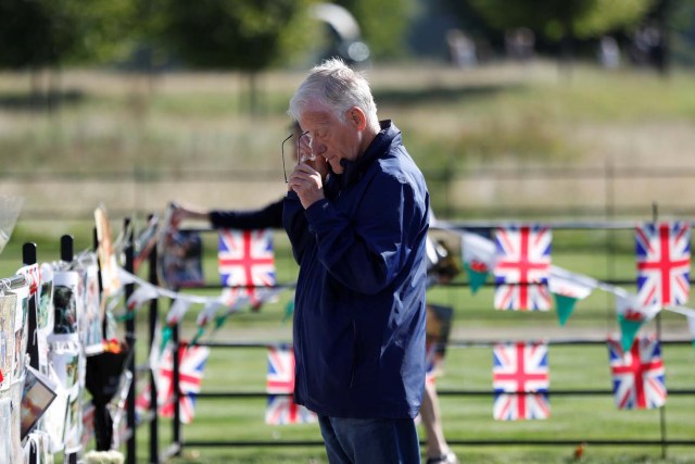 A man reacts as he looks at flowers and tributes left in memory of the late Princess Diana, at the gates of her former residence in Kensington Palace on the twentieth anniversary of her death, in London, Britain August 31, 2017. REUTERS/Peter Nicholls