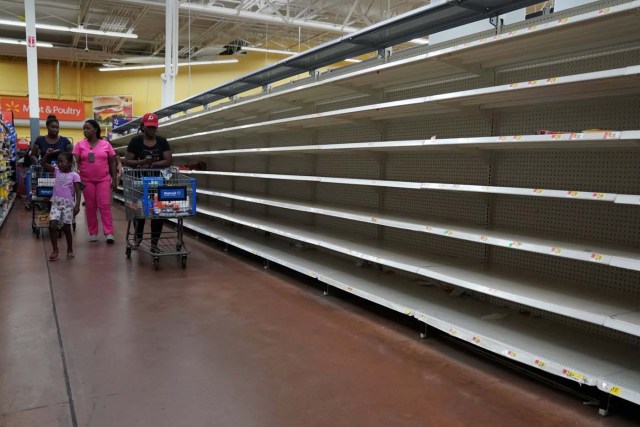 People walk past empty shelves where bread is normally sold in a Walmart store in advance of Hurricane Irma's expected arrival in North Miami Beach, Florida, U.S., September 7, 2017. REUTERS/Carlo Allegri