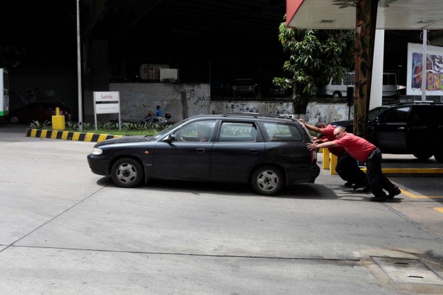 Gas station attendants push a car at a gas station of Venezuelan state-owned oil company PDVSA in Caracas, Venezuela September 21, 2017. REUTERS/Marco Bello