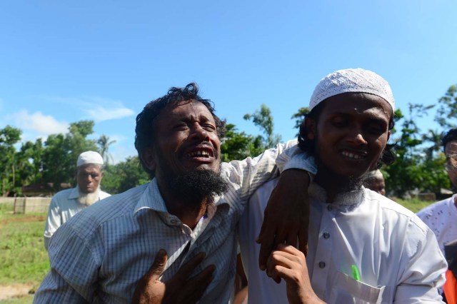 Rohingya refugees Alif Jukhar (L) reacts after burying both parents, who died when their boat capsized when crossing from Myanamr into Bangladesh, at a graveyard in Sha Porir Dwip in Teknaf on October 9, 2017. Alif Jukhar, a Rohingya refugee who has long lived in Bangladesh, lost nine relatives in the disaster including his mother and father. At least 12 Rohingya refugees, most of them children, drowned and scores more were missing on Ocotber 9 after their overloaded boat capsized in the latest tragedy to strike those fleeing violence in Myanmar. / AFP PHOTO / MUNIR UZ ZAMAN