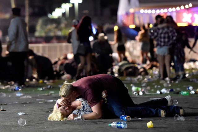 LAS VEGAS, NV - OCTOBER 01: A man lays on top of a woman as others flee the Route 91 Harvest country music festival grounds after a active shooter was reported on October 1, 2017 in Las Vegas, Nevada. A gunman has opened fire on a music festival in Las Vegas, leaving at least 2 people dead. Police have confirmed that one suspect has been shot. The investigation is ongoing.   David Becker/Getty Images/AFP