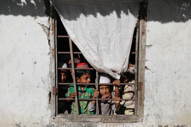 Students of a local madrasa watch from inside their classroom as bodies of Rohingya refugees from Myanmar, who were killed when their boat capsized on the way to Bangladesh, are brought to their school in Shah Porir Dwip, in Teknaf, near Cox's Bazar in Bangladesh, October 9, 2017. REUTERS/Damir Sagolj