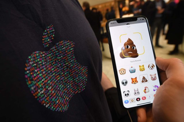 A member of Apple staff pose with a new Apple iPhone X smartphone showing new emoji features in Apple's Regent Street store in central London on November 3, 2017 after it opened for the first sales of the new smartphone. Apple's flagship iPhone X hit stores on November 3, as the world's most valuable company predicted bumper sales despite the handset's eye-watering price tag and celebrated a surge in profits. The device features facial recognition, cordless charging and an edge-to-edge screen made of organic light-emitting diodes used in high-end televisions. It marks the 10th anniversary of the first iPhone release and is released in about 50 markets around the world. / AFP PHOTO / Chris J Ratcliffe