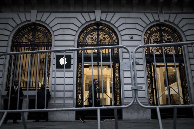 An Apple employee (C) walks past security personnels outside an Apple shop early morning on the release day of the new iPhone X in Paris on November 3, 2017. / AFP PHOTO / PHILIPPE LOPEZ