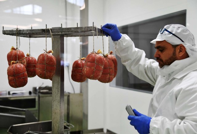 An employee controls mortadella at a stand during a press tour at FICO Eataly World agri-food park in Bologna on November 9, 2017. FICO Eataly World, said to be the world's biggest agri-food park, will open to the public on November 15, 2017. The free entry park, widely described as the Disney World of Italian food, is ten hectares big and will enshrine all the Italian food biodiversity. / AFP PHOTO / Vincenzo PINTO