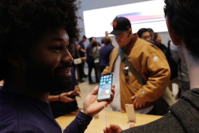 An Apple sales associate speaks with a customer waiting to purchase a new iPhone X in New York, U.S., November 3, 2017. REUTERS/Lucas Jackson