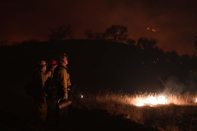 Firefighters light backfires as they try to contain the Thomas wildfire which continues to burn in Ojai, California on December 9, 2017. Brutal winds that fueled southern California's firestorm finally began to ease Saturday, giving residents and firefighters hope for respite as the destructive toll of multiple blazes came into focus. / AFP PHOTO / MARK RALSTON