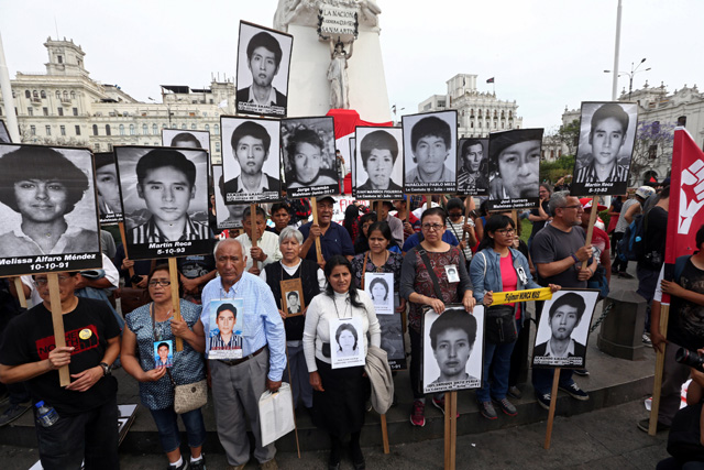 People holding pictures of victims of the guerrilla conflict in the 80s and 90s march after Peruvian President Pedro Pablo Kuczynski pardoned former President Alberto Fujimori in Lima, Peru, December 25, 2017. REUTERS/Mariana Bazo          NO RESALES. NO ARCHIVES.