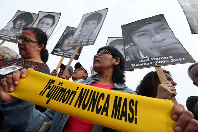 People holding pictures of victims of the guerrilla conflict in the 80s and 90s march after Peruvian President Pedro Pablo Kuczynski pardoned former President Alberto Fujimori in Lima, Peru, December 25, 2017.  Sign reads: "Fujimori never again!" REUTERS/Mariana Bazo         NO RESALES. NO ARCHIVES.