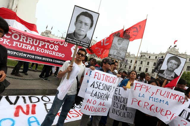 People holding pictures of victims of the guerrilla conflict in the 80s and 90s protest after Peruvian President Pedro Pablo Kuczynski pardoned former President Alberto Fujimori in Lima, Peru, December 25, 2017. REUTERS/Mariana Bazo           NO RESALES. NO ARCHIVES.