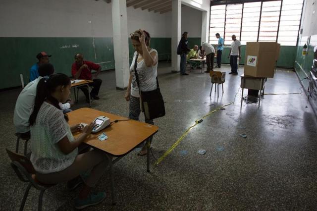Ciudadanos buscan su puesto de votación en las elecciones municipales hoy, domingo 10 de diciembre de 2017, en Caracas (Venezuela). Los centros de votación comenzaron a abrir hoy en Venezuela desde las 06.00 hora local (10.00 GMT) para la elección de 335 alcaldes y del gobernador del estado Zulia (oeste), una contienda en la que el grueso de la oposición no participará. EFE/NATHALIE SAYAGO