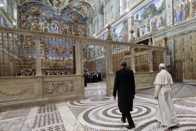 Pope Francis (R) arrives to pose for a family photo with diplomats accredited to the Holy See inside the Sistine Chapel, at the end of an audience for the traditional exchange of New Year greetings, at the Vatican, on January 8, 2018. / AFP PHOTO / POOL / Andrew Medichini