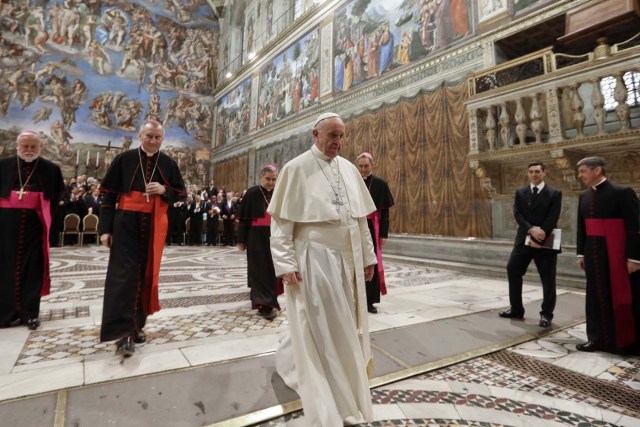 Pope Francis (C) leaves after posing for a family photo with diplomats accredited to the Holy See inside the Sistine Chapel, at the end of an audience for the traditional exchange of New Year greetings, at the Vatican, on January 8, 2018. / AFP PHOTO / POOL / Andrew Medichini