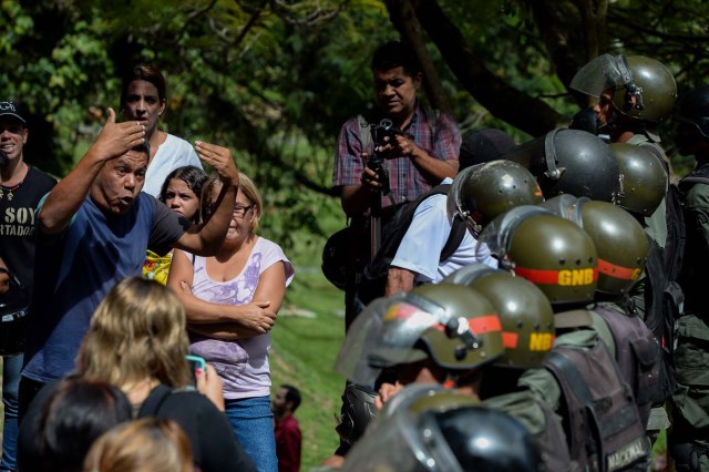 An activist opposing Venezuelan President Nicolas Maduro argues with security forces blocking their access to the funeral of Jose Diaz Pimentel and Abraham Agostini, two of the six other dissidents gunned down along with former elite police officer Oscar Perez in a bloody police operation, at a cemetery in Caracas on January 20, 2018. Perez, Venezuela's most wanted man since June when he flew a stolen police helicopter over Caracas dropping grenades on the Supreme Court and opening fire on the Interior Ministry, had gone on social media while the operation was under way on January 16 to say he and his group wanted to surrender but were under unrelenting sniper fire. That has raised questions about the government's account that the seven were killed after opening fire on police who had come to arrest them. / AFP PHOTO / Federico PARRA