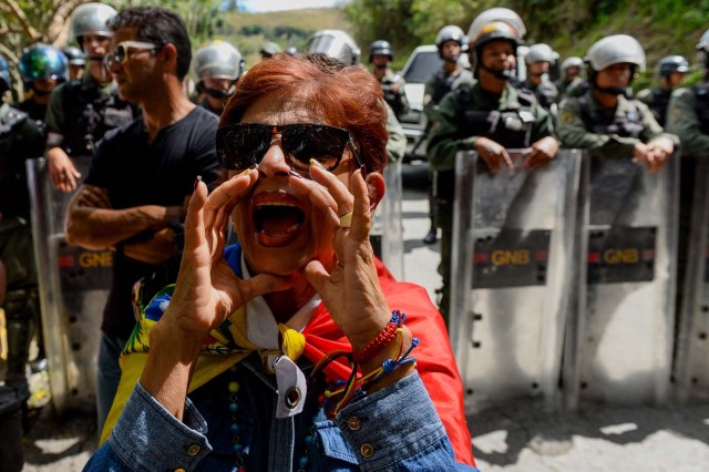 An activist opposing Venezuelan President Nicolas Maduro shouts slogans as security forces block their access to the funeral of Jose Diaz Pimentel and Abraham Agostini, two of the six other dissidents gunned down along with former elite police officer Oscar Perez in a bloody police operation, at a cemetery in Caracas on January 20, 2018. Perez, Venezuela's most wanted man since June when he flew a stolen police helicopter over Caracas dropping grenades on the Supreme Court and opening fire on the Interior Ministry, had gone on social media while the operation was under way on January 16 to say he and his group wanted to surrender but were under unrelenting sniper fire. That has raised questions about the government's account that the seven were killed after opening fire on police who had come to arrest them. / AFP PHOTO / Federico PARRA