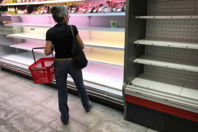 A woman looks at a partially empty refrigerator in a supermarket in Caracas, Venezuela January 9, 2018. REUTERS/Marco Bello