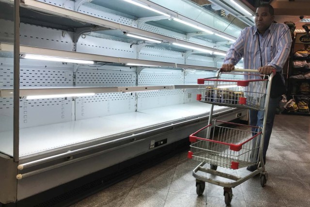 A man walks past an empty refrigerator at a supermarket in Caracas, Venezuela January 9, 2018. REUTERS/Marco Bello