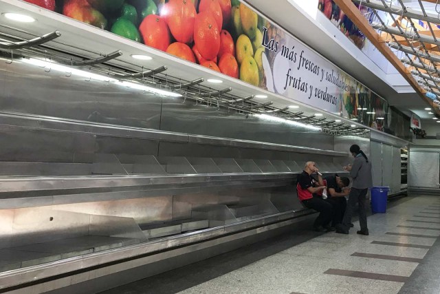 Workers sit on empty shelves at the fruit and vegetables area in a supermarket in Caracas, Venezuela January 10, 2018. REUTERS/Marco Bello