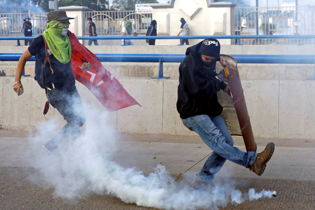 REFILE - CORRECTING GRAMMAR A demonstrator kicks a tear gas canister during a protest as Honduran President Juan Orlando Hernandez is sworn in for a new term in Tegucigalpa, Honduras, January 27, 2018. REUTERS/Edgard Garrido
