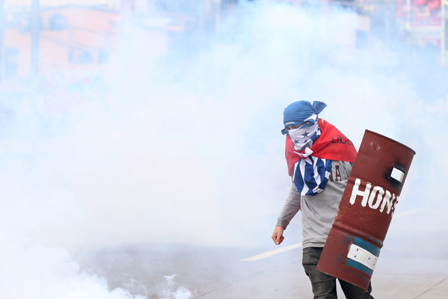 REFILE - CORRECTING GRAMMAR A demonstrator is pictured between the tear gas during a protest as Honduras' President Juan Orlando Hernandez is sworn in for a new term in Tegucigalpa, Honduras, January 27, 2018. REUTERS/Edgard Garrido