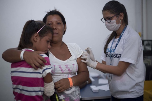 A Venezuelan refugee woman and her daughter receive vaccines provided by the local government at the city of Boa Vista, Roraima, Brazil, on February 24, 2018. When the Venezuelan migratory flow exploded in 2017 the city of Boa Vista, the capital of Roraima, 200 kilometres from the Venezuelan border, began to organise shelters as people started to settle in squares, parks and corners of this city of 330,000 inhabitants of which 10 percent is now Venezuelan. / AFP PHOTO / MAURO PIMENTEL