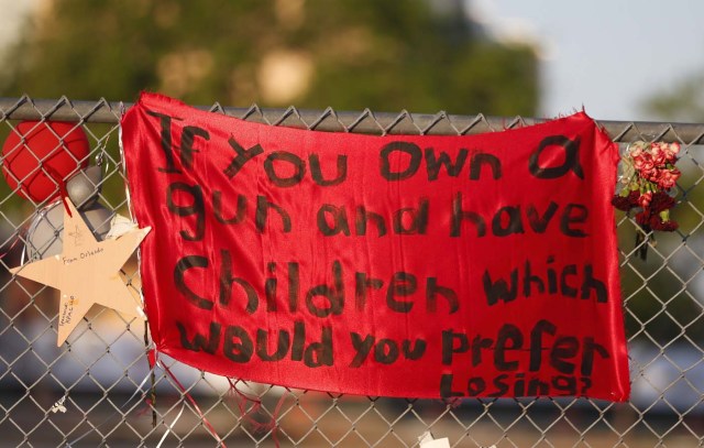 A a sign hangs on a fence one at Marjory Stoneman Douglas High School in Parkland, Florida on February 27, 2018. Florida's Marjory Stoneman Douglas high school will reopen on February 28, 2018 two weeks after 17 people were killed in a shooting by former student, Nikolas Cruz, leaving 17 people dead and 15 injured on February 14, 2018. / AFP PHOTO / RHONA WISE