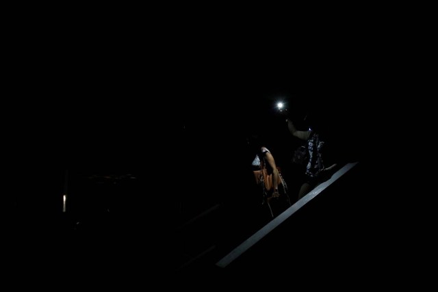 People use light from a phone while they walk on the staircase of a parking garage during a blackout in Caracas, Venezuela February 6, 2018. REUTERS/Carlos Garcia Rawlins