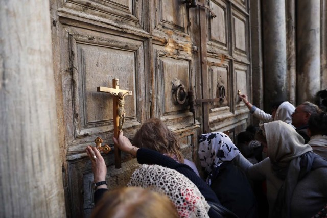 Pilgrims pray outside the closed gate of the Church of the Holy Sepulchre in Jerusalem's Old City on February 27, 2018. The church in Jerusalem built at the traditional site of Jesus's burial remained closed for a third day as Christian leaders protested against Israeli tax measures and a controversial proposed law. / AFP PHOTO / Thomas COEX