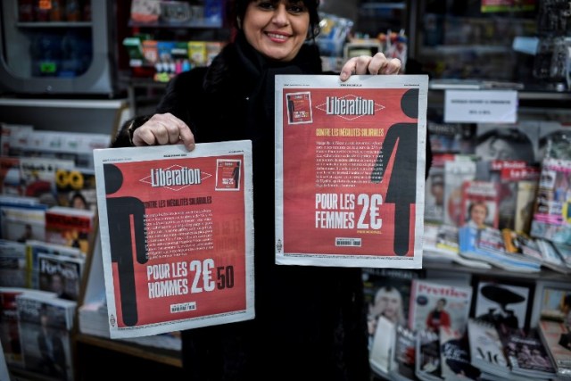 A woman holds the two different front pages of the French daily newspaper Liberation during the International Woman's Day on March 8, 2018 in Paris. / AFP PHOTO / STEPHANE DE SAKUTIN
