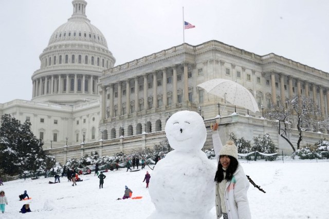 WASHINGTON, DC - MARCH 21: A tourist poses next to a 7-foot-tall snow man in front of the U.S. Capitol March 21, 2018 in Washington, DC. An early spring storm brought several inches of snow to the East Coast, the fourth nor'easter in recent weeks.   Chip Somodevilla/Getty Images/AFP