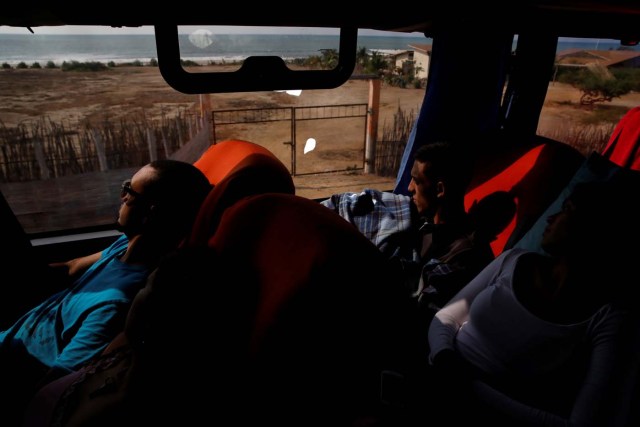 Carlos Rivero (L) and Adrian Naveda (C), traveling by bus from Caracas to Chile, look out of the window while they drive through Zorritos, Peru, November 11, 2017. "I think we waited too long to leave" said Carlos Rivero, 31, a former security operator for the Caracas metro. The road the bus travels along in northern Peru goes through through tiny villages near the seashore. REUTERS/Carlos Garcia Rawlins SEARCH "RAWLINS BUS" FOR THIS STORY. SEARCH "WIDER IMAGE" FOR ALL STORIES. TPX IMAGES OF THE DAY.