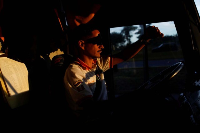 Wilder Perez uses his hand to shade himself from the setting sun as he drives a Rutas de America bus through Valencia, Venezuela, November 7, 2017. REUTERS/Carlos Garcia Rawlins SEARCH "RAWLINS BUS" FOR THIS STORY. SEARCH "WIDER IMAGE" FOR ALL STORIES. TO MATCH SPECIAL REPORT XXX