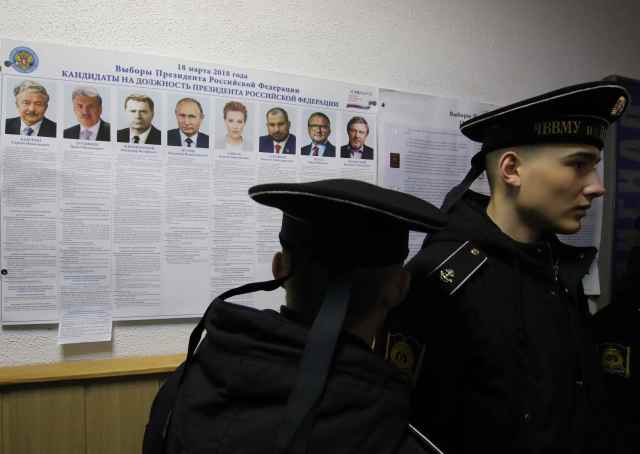 Russian navy sailors gather near a broadsheet with information about the candidates at a polling station during the Russian presidential election in Sevastopol, Crimea March 18, 2018. REUTERS/Pavel Rebrov