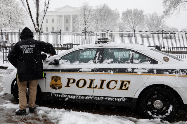 U.S. Secret Service police officer clears his car from snow in front of the White House during a snowstorm in Washington, U.S., March 21, 2018. REUTERS/Yuri Gripas