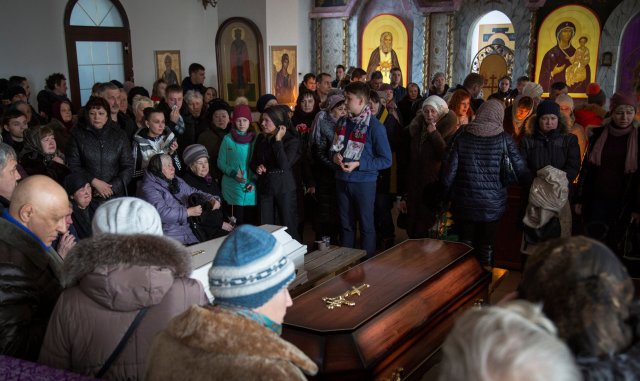 People stay next to caskets with the victims of a shopping mall fire during a funeral ceremony in cathedral in Kemerovo, Russia March 28, 2018. REUTERS/Maksim Lisov NO RESALES. NO ARCHIVES