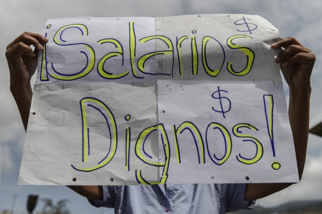 A patient holds a banner reading "Worthy Salaries" during a protest by health workers and patients for the lack of medicines, medical supplies and poor conditions in hospitals, in Caracas on April 17, 2018. Doctors and nurses protest against the health crisis in Venezuela, currently in the midst of a deep economic and political crisis and where health authorities have reported a rise in vaccine-preventable diseases. / AFP PHOTO / Luis ROBAYO