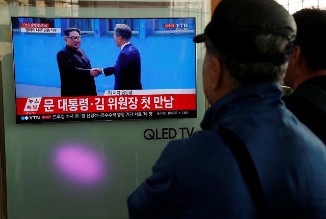 People watch a TV showing a live broadcast of the inter-Korean summit and South Korean President Moon Jae-in shaking hands with North Korean leader Kim Jong Un, at a railway station in Seoul, South Korea, April 27, 2018. REUTERS/Jorge Silva