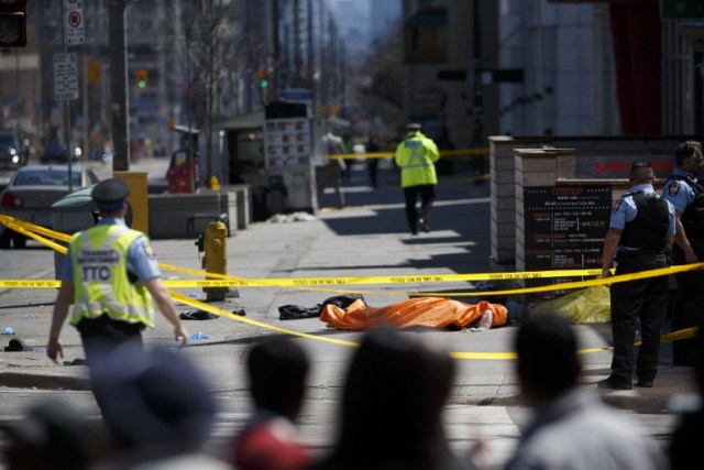  TORONTO, ON - 23 DE ABRIL: Una lona coloca sobre un cuerpo en Yonge St. en Finch Ave. después de que una camioneta se estrelló contra los peatones el 23 de abril de 2018 en Toronto, Canadá. Un sospechoso está bajo custodia luego de que una furgoneta blanca chocara con múltiples peatones. Cole Burston / Getty Images / AFP